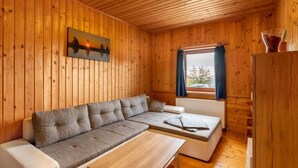 A cozy cabin with a wooden interior, a sofa, a small table, and a window with curtains.
