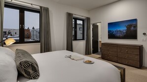 Une chambre d’hôtel avec un lit, une commode, une fenêtre avec des rideaux, une lampe et un tableau au mur.