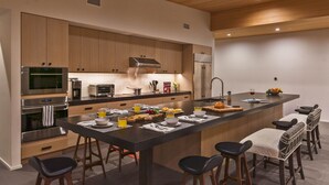 Une cuisine moderne dotée d’un îlot central, de tabourets de bar et d’un coin repas pour le petit-déjeuner.
