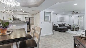 Una cocina moderna con comedor, una sala de estar con sofá y mesa de centro, y un ventilador de techo.