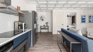 A modern kitchen with a built-in oven, a coffee machine, and a refrigerator. There is a dining area with a bench and a table.