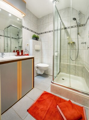 Enjoy a refreshing shower or soak in the bathtub, with a large mirror and convenient amenities nearby.