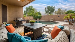 A patio with a pool, outdoor furniture, and a grill. - 4-BR Home with a Private Heated Pool (Litchfield Park)