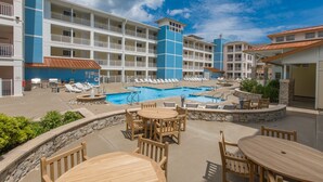 Um hotel com piscina, área de estar externa e um edifício de vários andares com varandas.