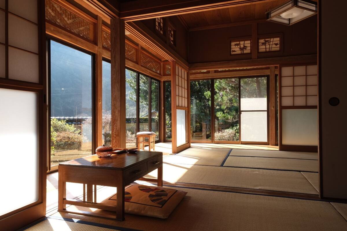 Una habitación japonesa tradicional con suelo de tatami, una mesa de madera baja y puertas correderas.