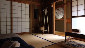 A traditional Japanese room with tatami flooring, shoji screens, and a futon bed. - Shimanto Riverside Hideaway (Shimanto)