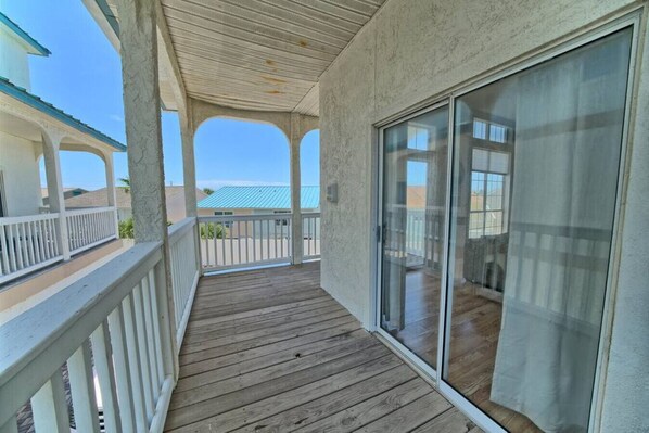A wooden deck with a glass door leading to a room.