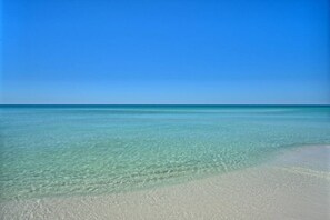 A clear view of a beach with shallow, clear water and a sandy shore.