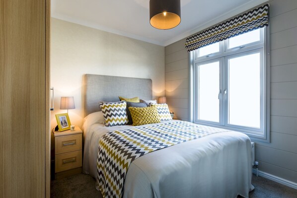 A bedroom with a bed, bedside tables, a lamp, and a window with curtains.