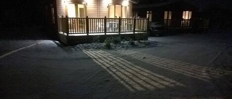 Een huis met een houten terras en een oprit vol sneeuw.