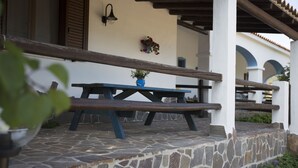 A stone-paved patio with a wooden bench and a potted plant. - Country house Comfort apartment with parking place (Sardegna)