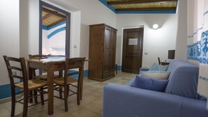 A room with a dining table, chairs, a sofa, and a wooden cabinet. - Country house Comfort apartment with parking place (Sardegna)