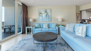 Ein Wohnzimmer mit einem blauen Sofa, einem Couchtisch und einem Gemälde an der Wand.