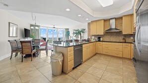 Een moderne keuken met een groot eiland, houten kastjes en roestvrijstalen apparatuur.