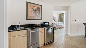 Een moderne keuken met roestvrijstalen apparatuur, een zwart aanrecht en een kunstwerk in een lijst boven de gootsteen.