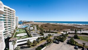 Un hôtel de grande hauteur doté de nombreux balcons offrant une vue sur une plage et l’océan.