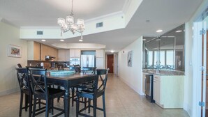 A spacious kitchen with a dining area, featuring a chandelier, granite countertops, and a large island with a dishwasher. - Cozy Three Bedroom with Spectacular Gulf Views! Complimentary Boat Slip! (Orange Beach)
