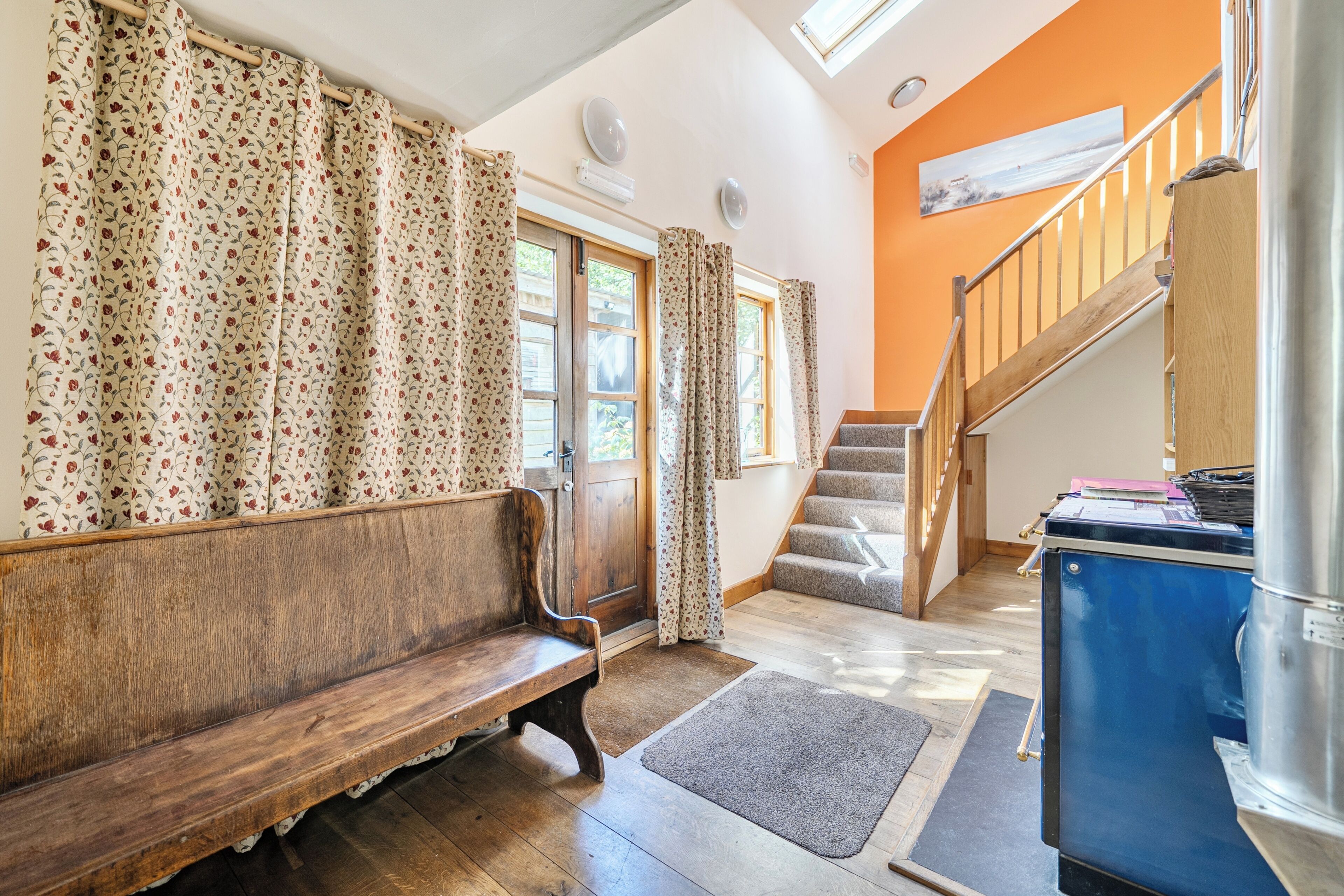 Un interior acogedor con un banco de madera, una escalera y un mueble azul.
