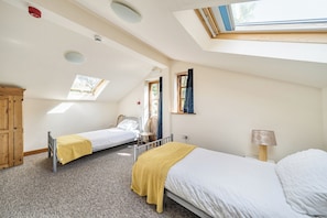 A room with two beds, a skylight, a window, a wooden wardrobe, and a bedside table. - 3-bed Barn Eco-lodge on the Tarka Trail (Torrington)