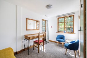 A room with a desk, two chairs, a window with a view of trees, and a ceiling light. - 3-bed Barn Eco-lodge on the Tarka Trail (Torrington)