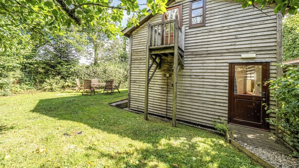 A wooden cabin with a deck, a window, and a door. - 3-bed Barn Eco-lodge on the Tarka Trail (Torrington)