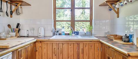 A kitchen with wooden cabinets, a window, and various kitchen utensils.