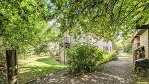 A wooden cabin with a gravel driveway and a wooden fence. - 3-bed Barn Eco-lodge on the Tarka Trail (Torrington)