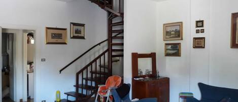 A living room with a staircase, a blue sofa, a wooden coffee table, and a dining table.