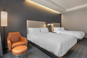 A hotel room with a large bed, a chair, and a bedside table.