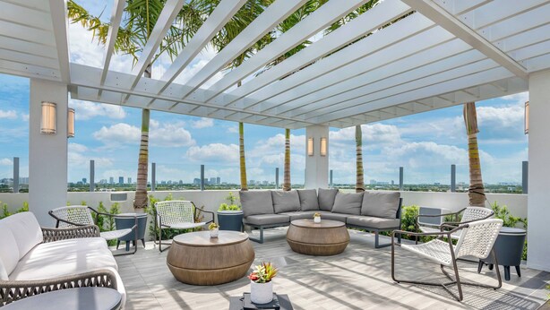 Terraza en la azotea con una pérgola blanca, mobiliario exterior y vistas a un horizonte urbano.