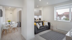 Una sala de estar moderna con un sofá gris, una mesa de comedor con sillas y una alfombra estampada.