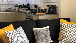 Una cocina moderna con azulejos blancos, encimera negra y varios electrodomésticos.