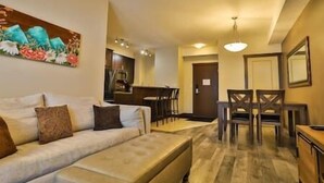Ein Wohnzimmer mit einer Couch, ein Essbereich mit Tisch und Stühlen sowie eine Küche im Hintergrund.