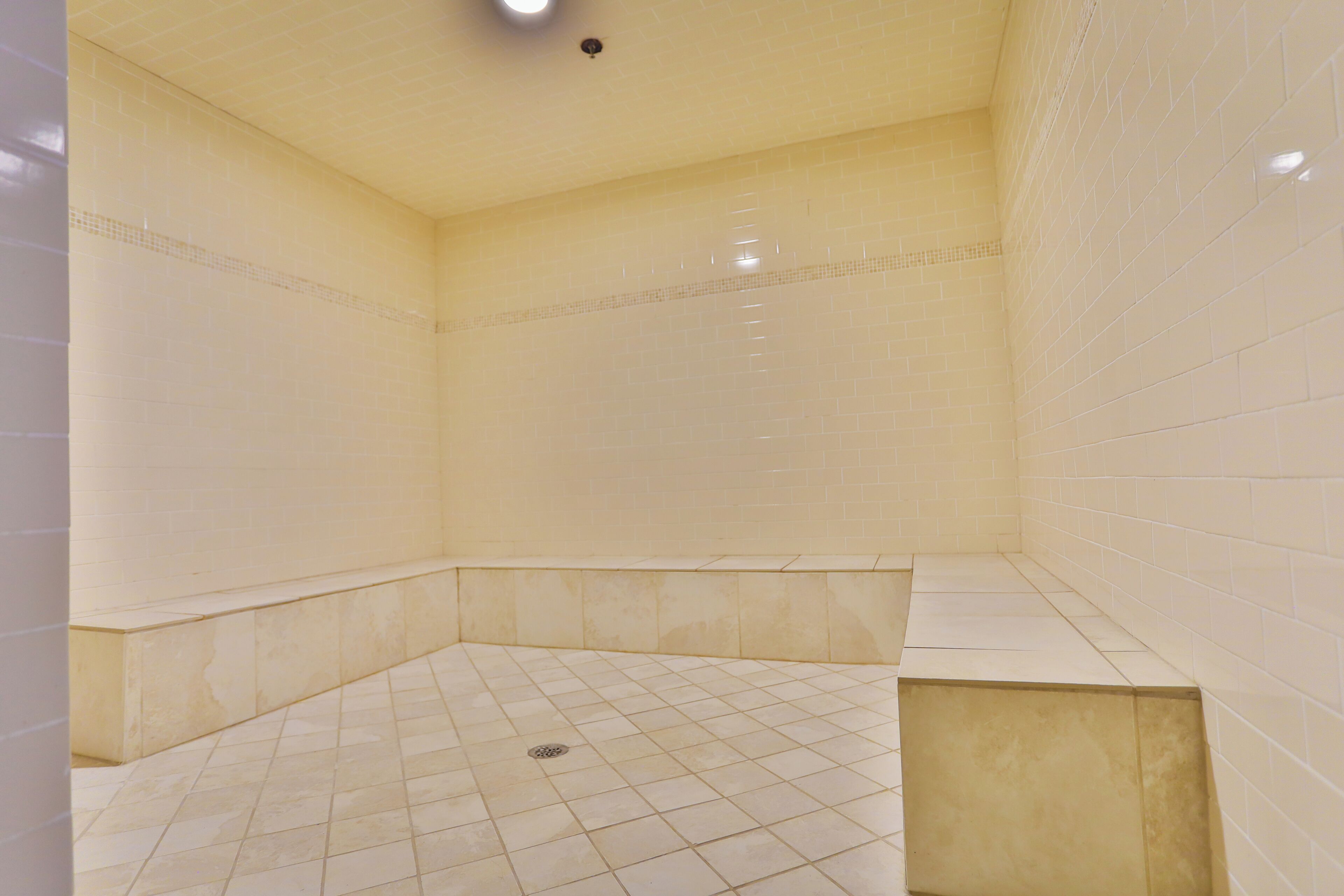 Un baño pequeño con azulejos, zona de ducha y un banco.