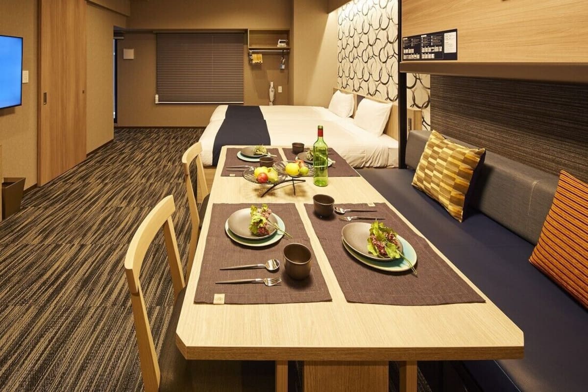 Ein Hotelzimmer mit Essbereich, einem Bett, einem Fernseher und einer an der Wand befestigten Speisekarte.