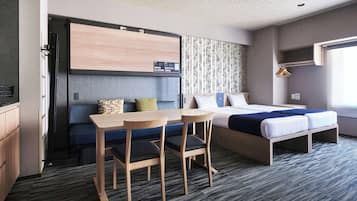 Una habitación de hotel compacta con kitchenette, una cama, un escritorio y una zona de estar.