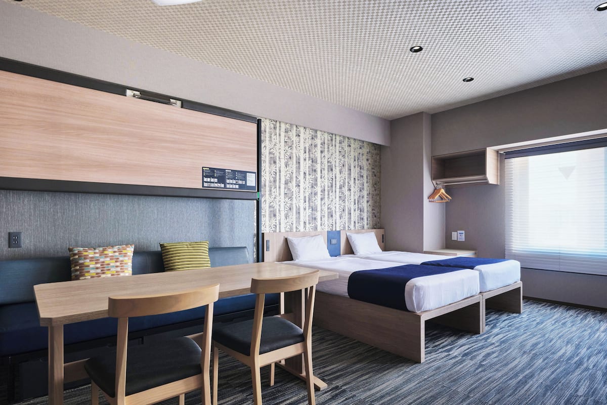 Ein Hotelzimmer mit einem Bett, zwei Stühlen, einem Schreibtisch und einem kleinen Tisch.