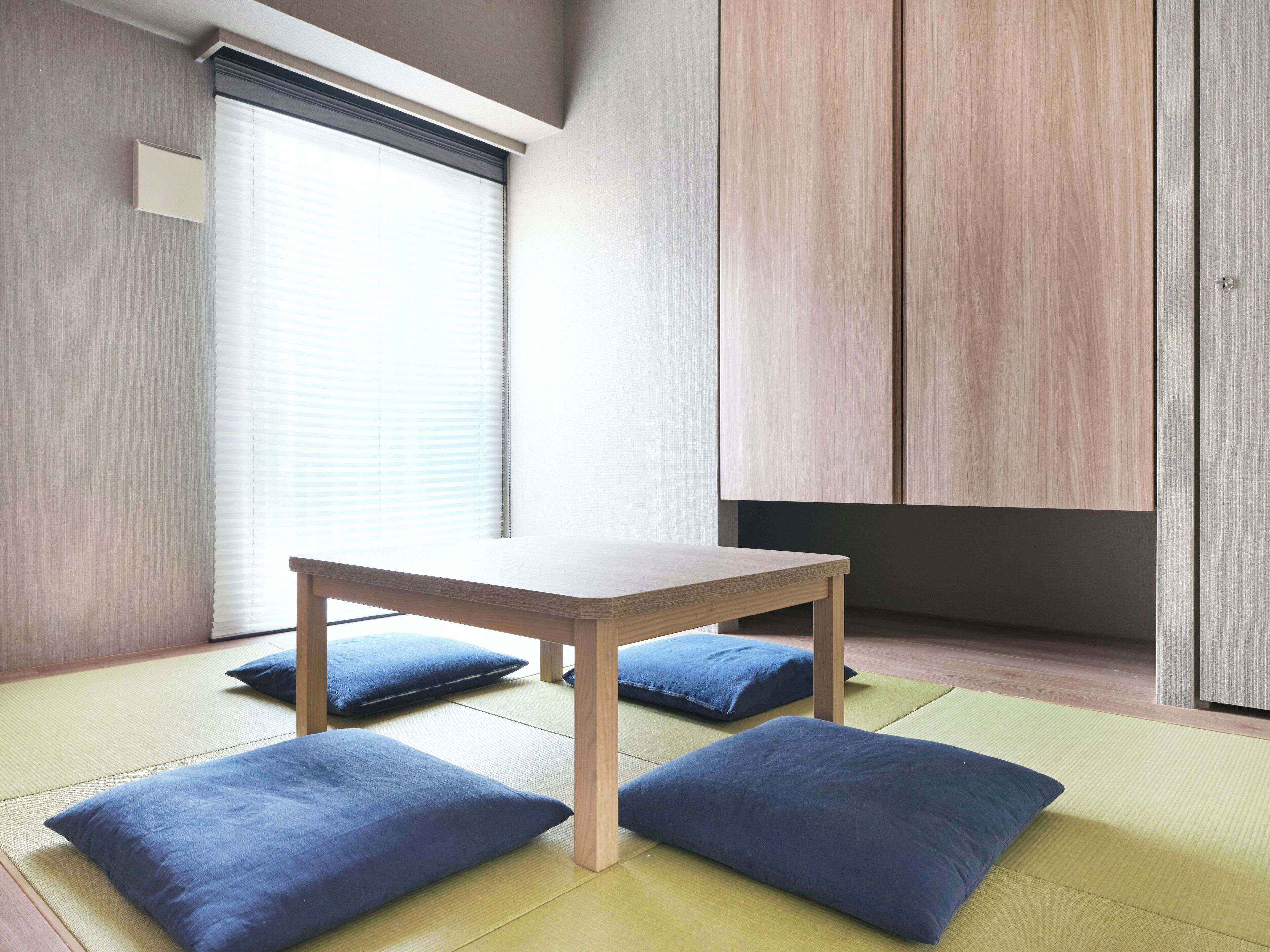 A room with tatami mats, a wooden table, and blue cushions.