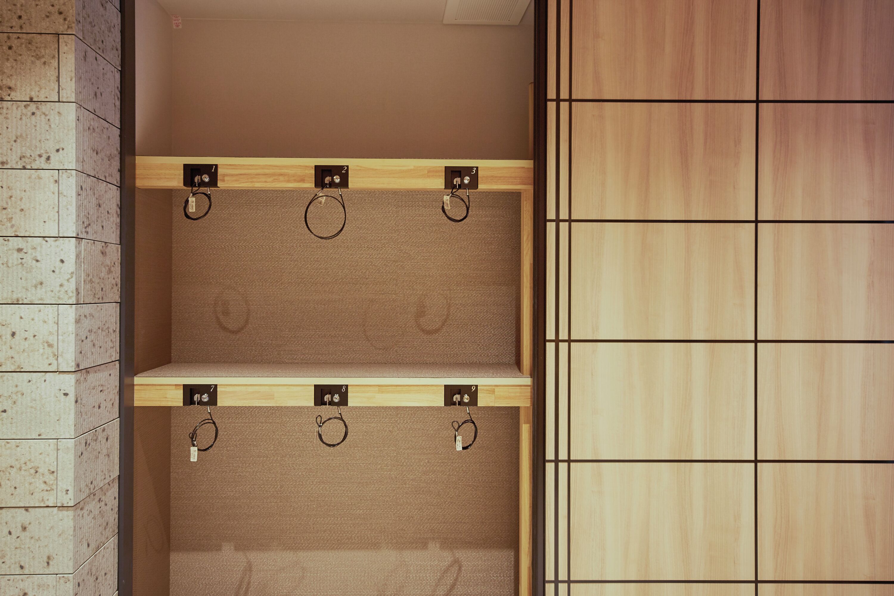 A restroom with three towel racks and a wooden shelf.