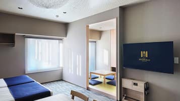 Habitación de hotel con cama, escritorio, silla, televisión y vistas al exterior.
