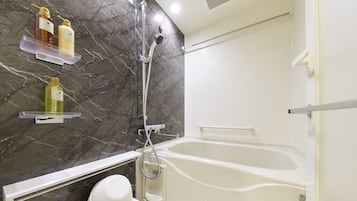 A bathroom with a bathtub, a shower, and a toilet. There are shelves with toiletries.