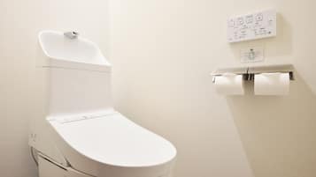 A modern toilet with a control panel, a toilet paper holder, and a wall-mounted sign with Japanese text.