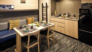 A compact kitchen with a dining table, chairs, and a sofa with cushions. - MONday Apart Premium Akihabara (Tokyo)