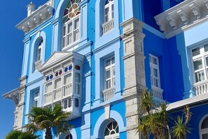 A multi-story building with a blue facade, white trim, and classical architectural details. - Apartamento Italia Colombres (Colombres)
