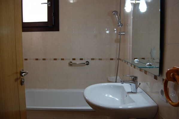 A bathroom with a bathtub, a sink, a glass shower enclosure, and a mirror. - Apartamento Italia Colombres (Colombres)