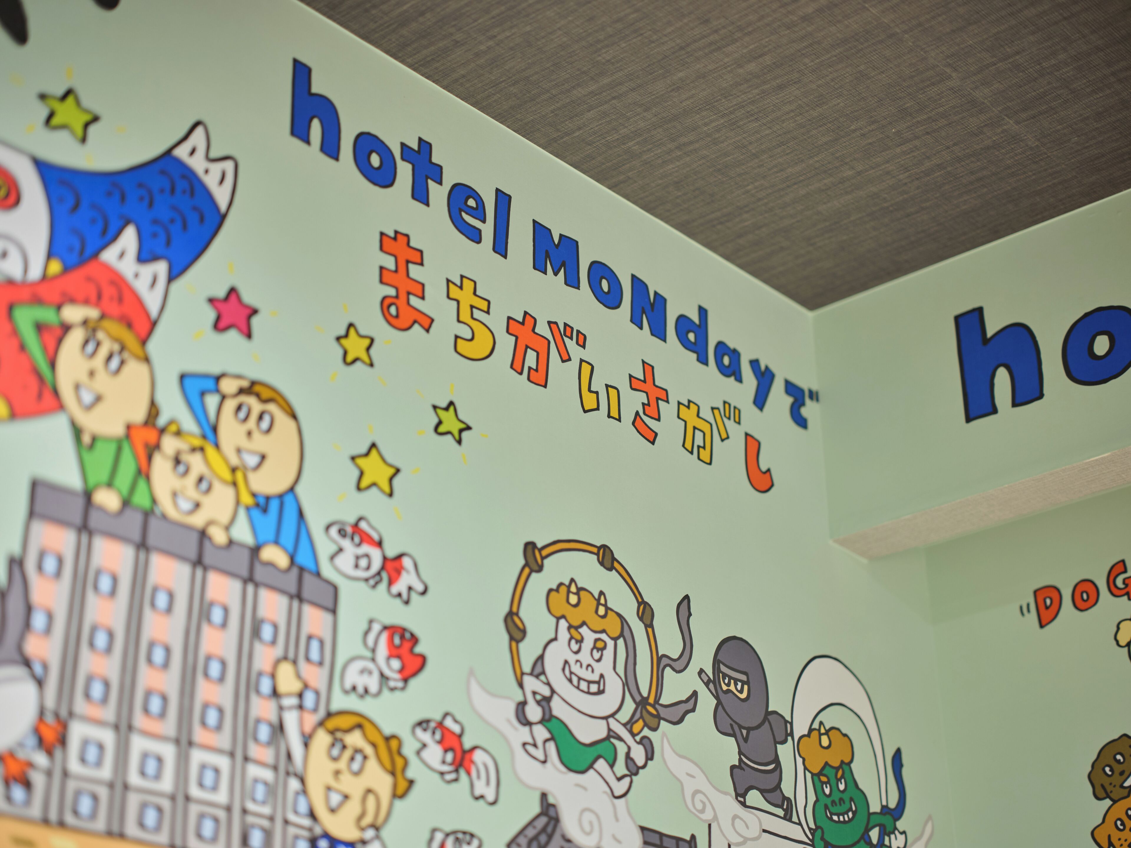 A wall with cartoon characters and Japanese text indicating a hotel named 'Hotel Monday.'