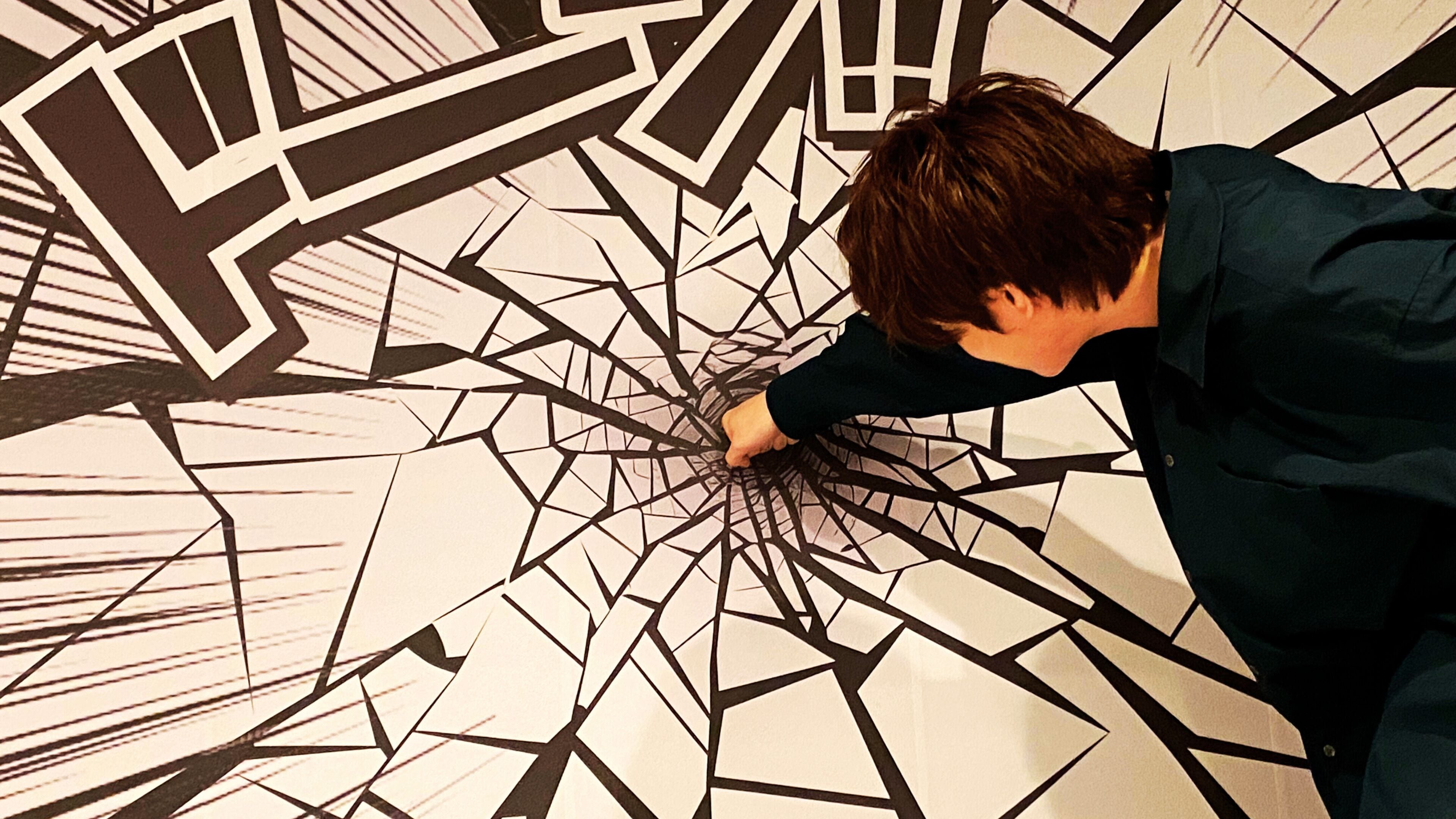 A person interacting with a geometric wall design.