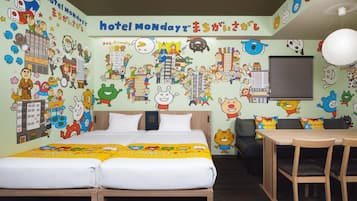 A hotel room with a bed, a desk, and chairs. The walls are decorated with colorful cartoon characters and text.