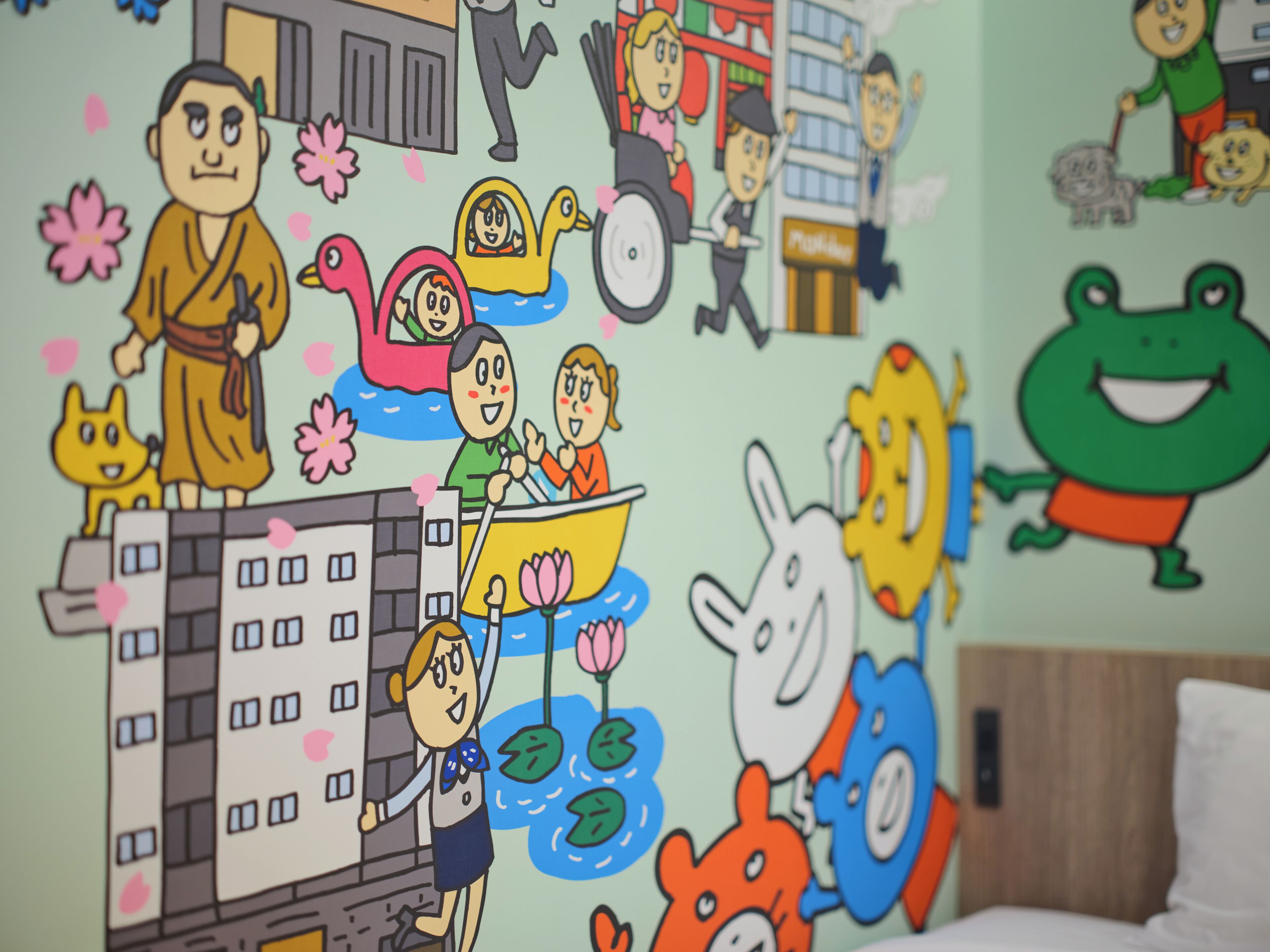 A wall with various cartoon characters and animals, a building illustration, and a bed with a wooden headboard.