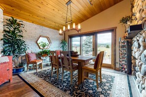 Relax in this inviting space with a large window offering a view of the outdoors, a dining area, and potted plants.